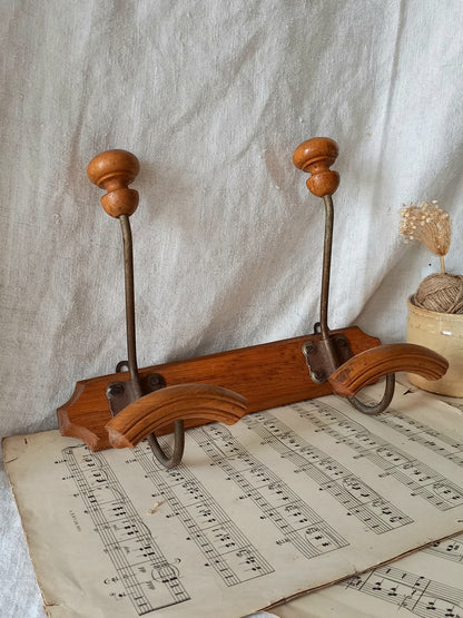 French vintage coat and hat rack with 2 metal hooks, each hook having wooden pegs for a hat and a coat.
