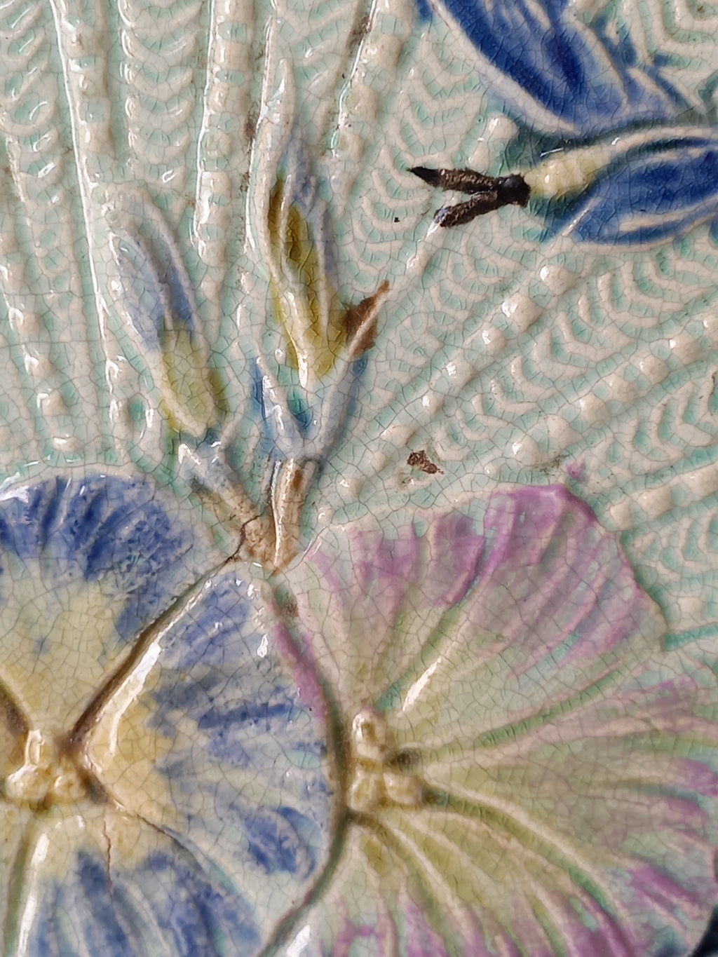 Close-up of antique Wasmuel blue floral majolica plate with designs in relief.