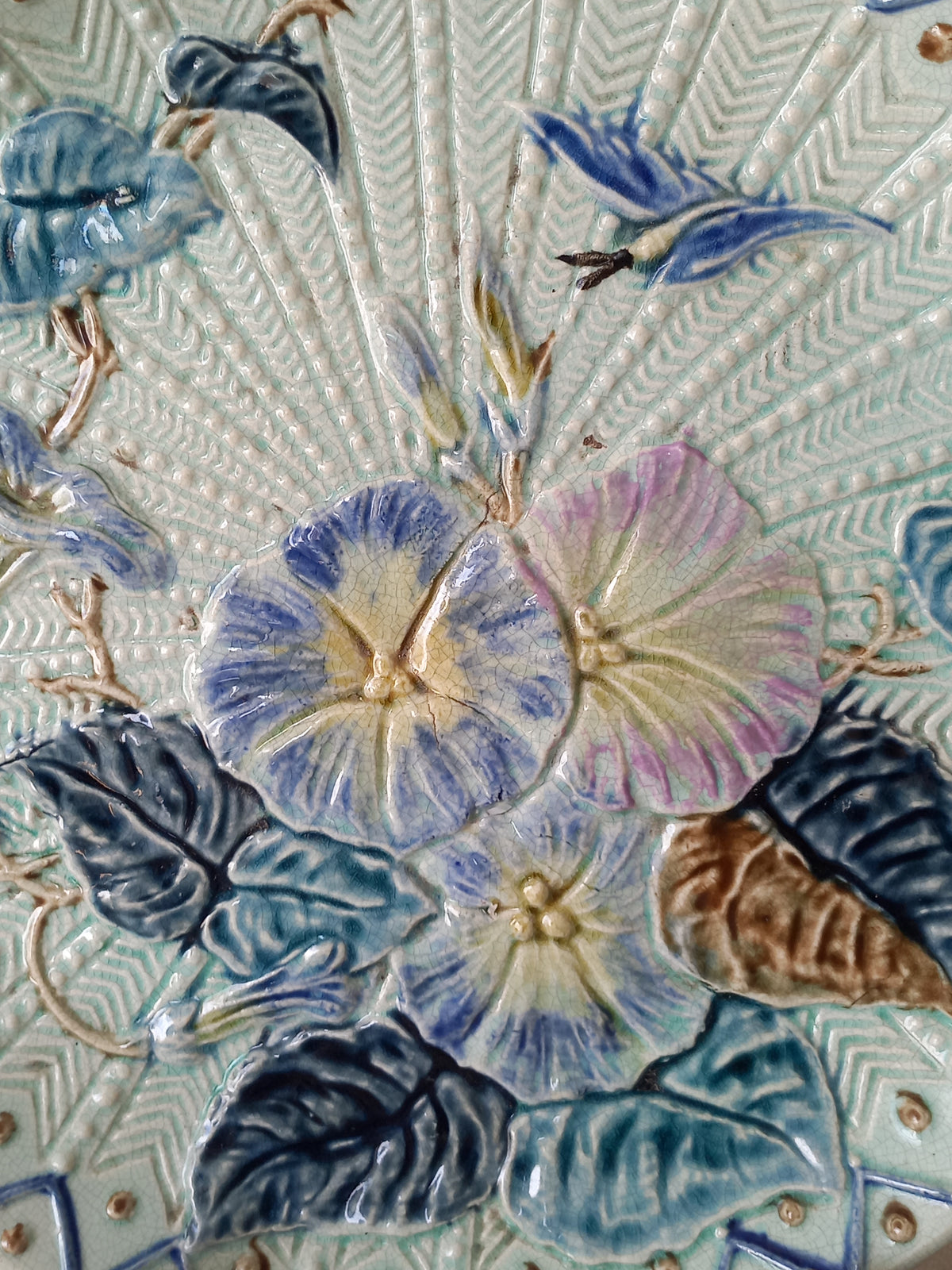 Close-up of antique Wasmuel blue floral majolica plate with designs in relief.