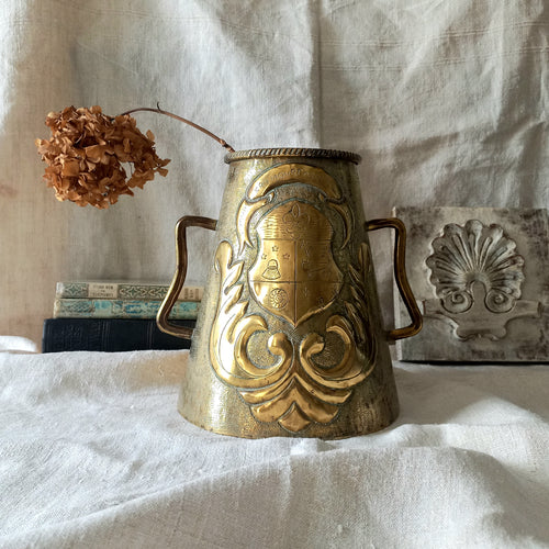 A decorative vintage/antique brass vase with a coat of arms - an unusual piece of brass ware likely a tourist piece inspired by old fountains that were often decorated with a family, commune or regional coat of arms. These days it could have many uses including stand-alone home decor, a decorative vase, or maybe a planter (if considering as a planter the top opening is: 10.7 cm (just over 4'').