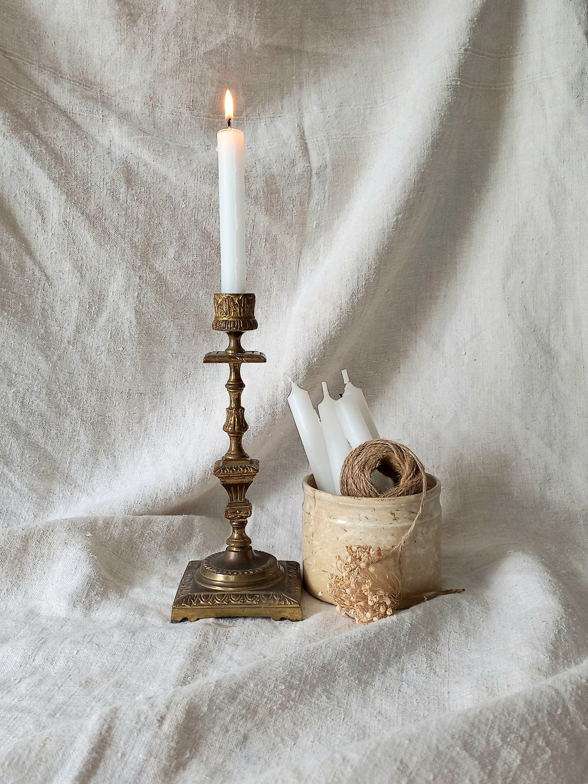 Decorative candlestick with a lit candle on a textured fabric background