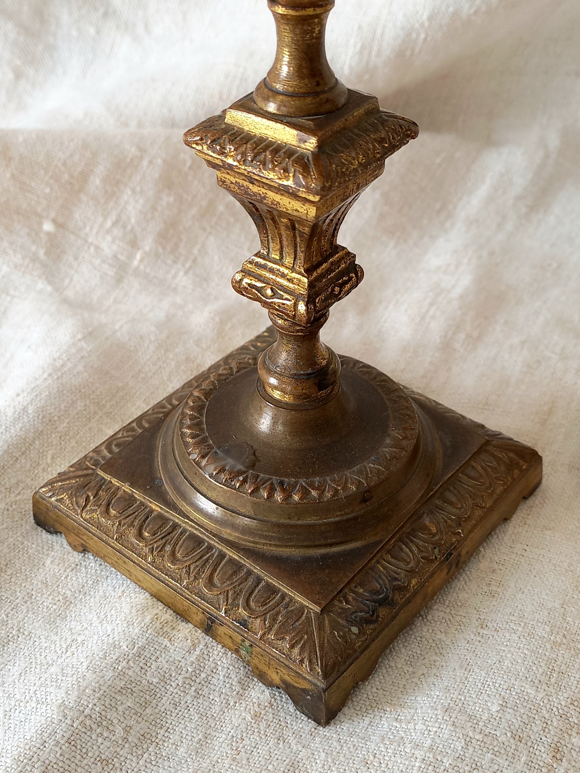 Decorative bronze candle holder on a textured white surface