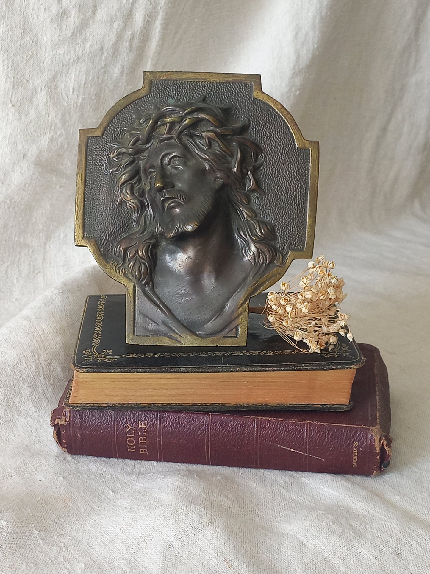 Bronze table-top Crucifix with a Jesus Christ bust design on a textured surface