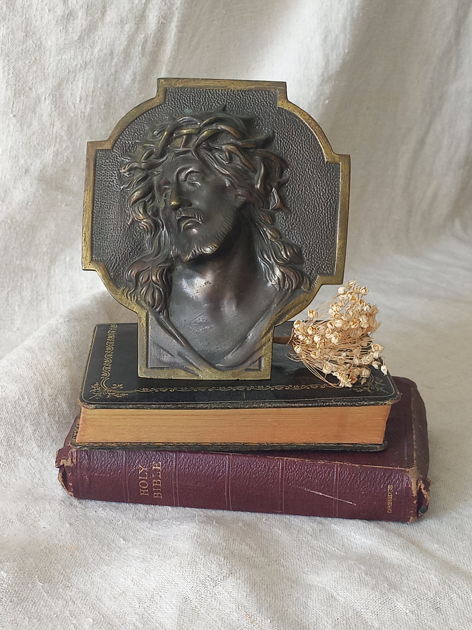 Bronze table-top Crucifix with a Jesus Christ bust design on a textured surface
