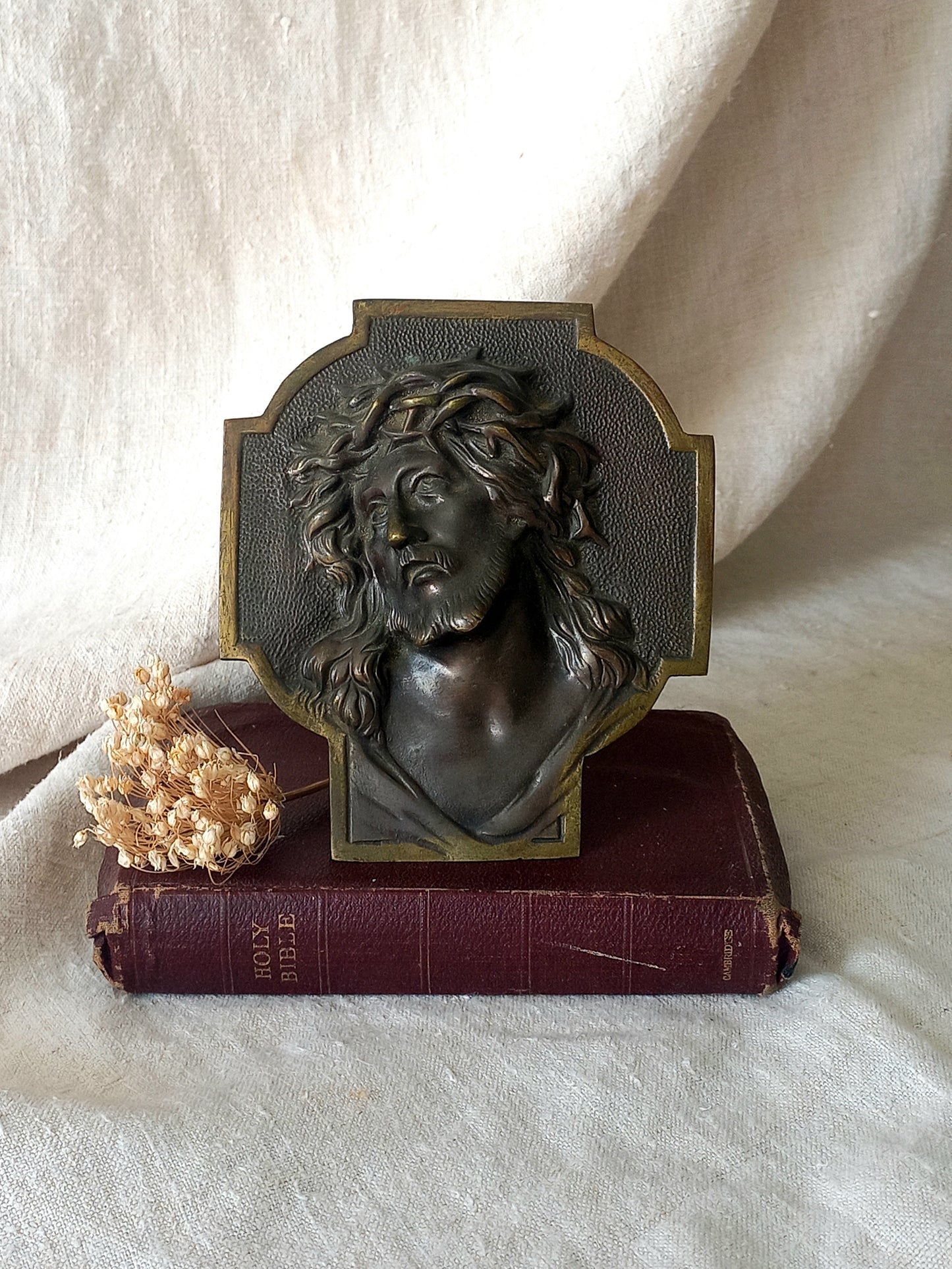 Bronze table-top Crucifix with a Jesus Christ bust design on a textured surface