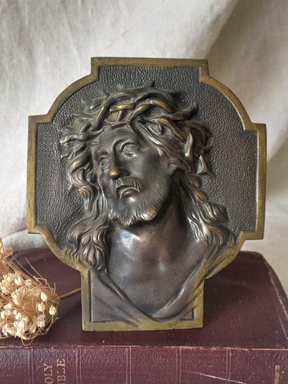 Bronze table-top Crucifix with a Jesus Christ bust design on a textured surface