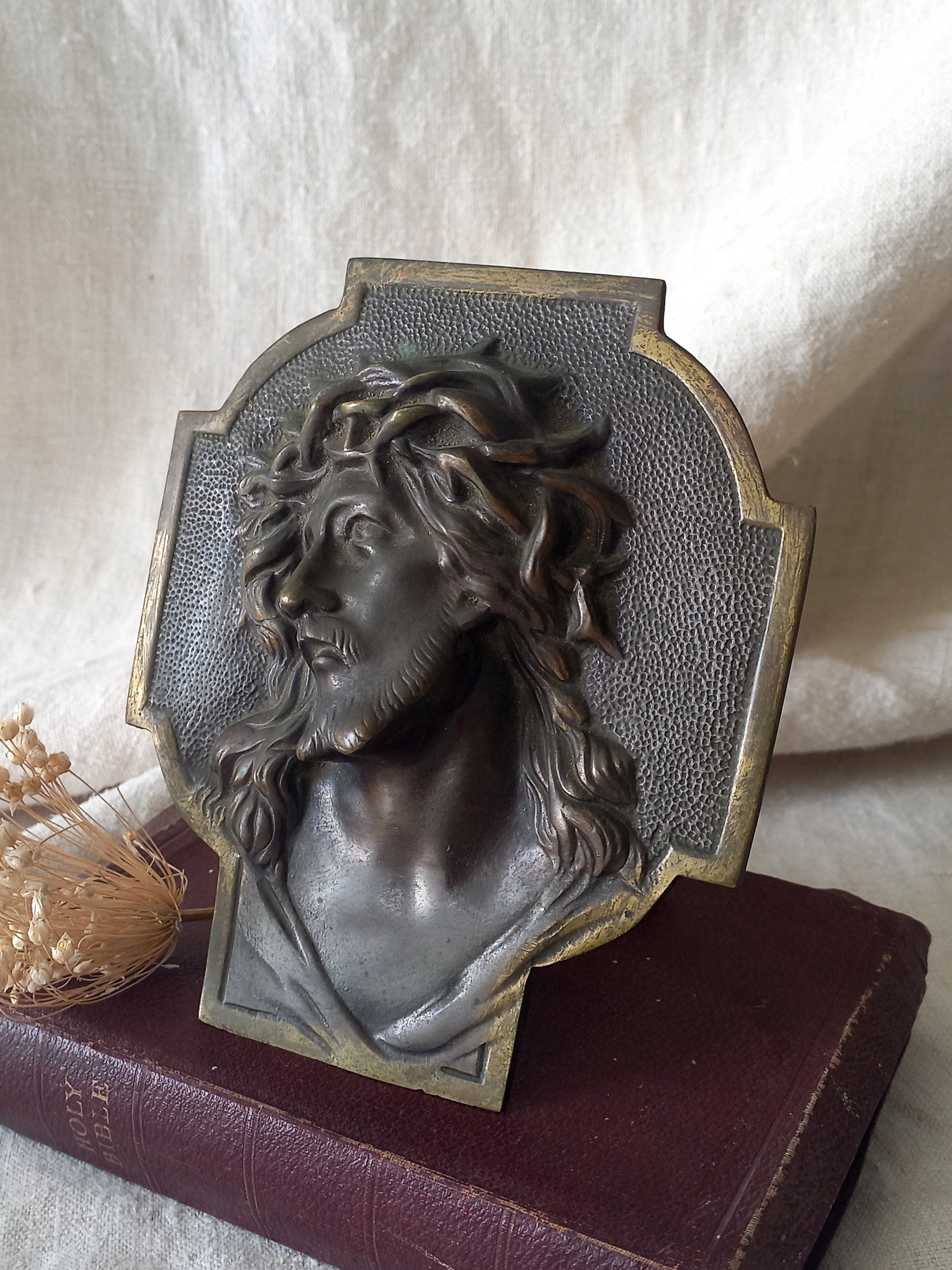 Decorative plaque with a bust of a person wearing a wreath on a textured surface