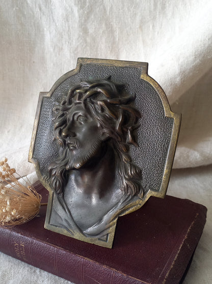 Decorative plaque with a bust of a person wearing a wreath on a textured surface