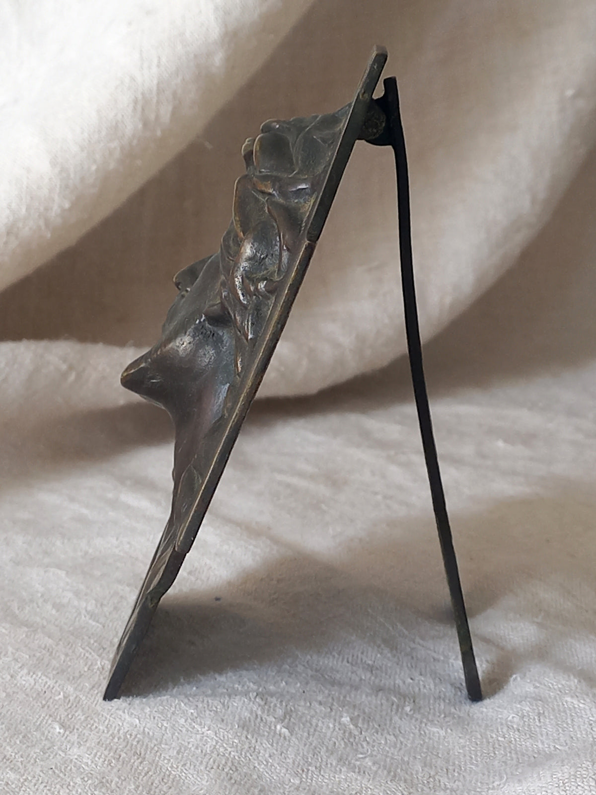 Side view of Bronze table-top Crucifix with a Jesus Christ bust design on a textured surface