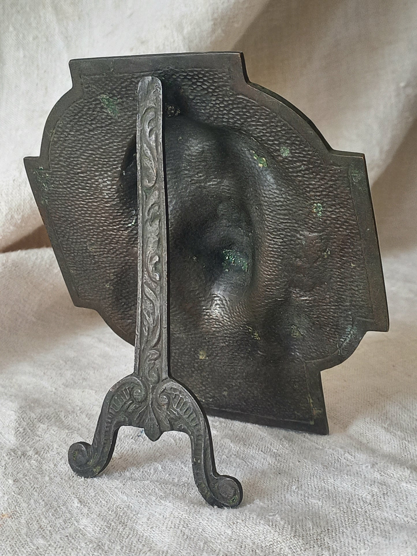 Rear of a bronze table-top Crucifix with a Jesus Christ bust design on a textured surface
