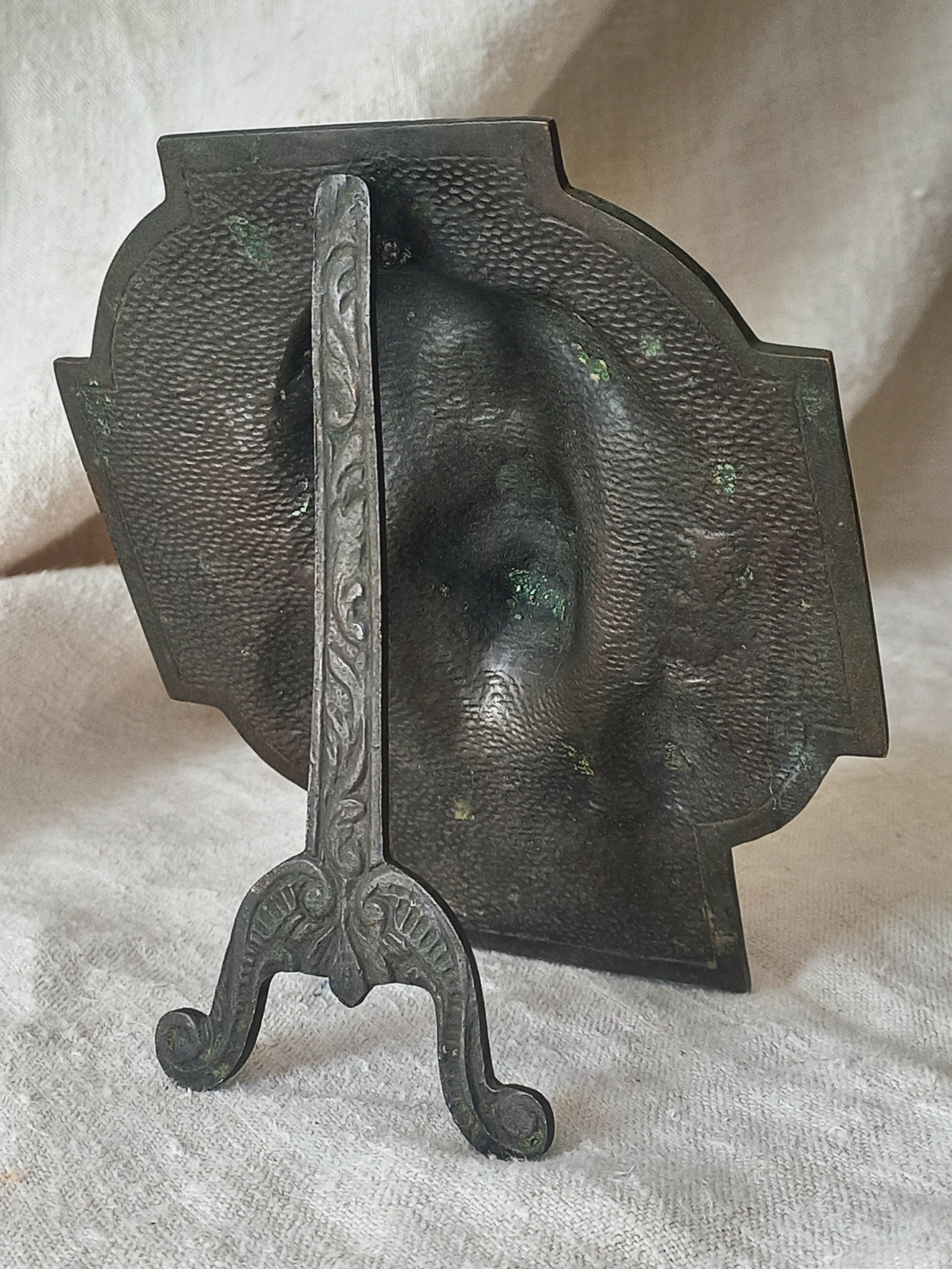Rear of a bronze table-top Crucifix with a Jesus Christ bust design on a textured surface