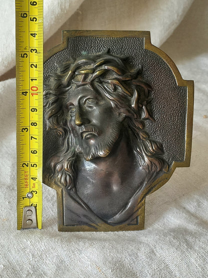 Bronze table-top Crucifix with a Jesus Christ bust design on a textured surface with a tape measure for reference