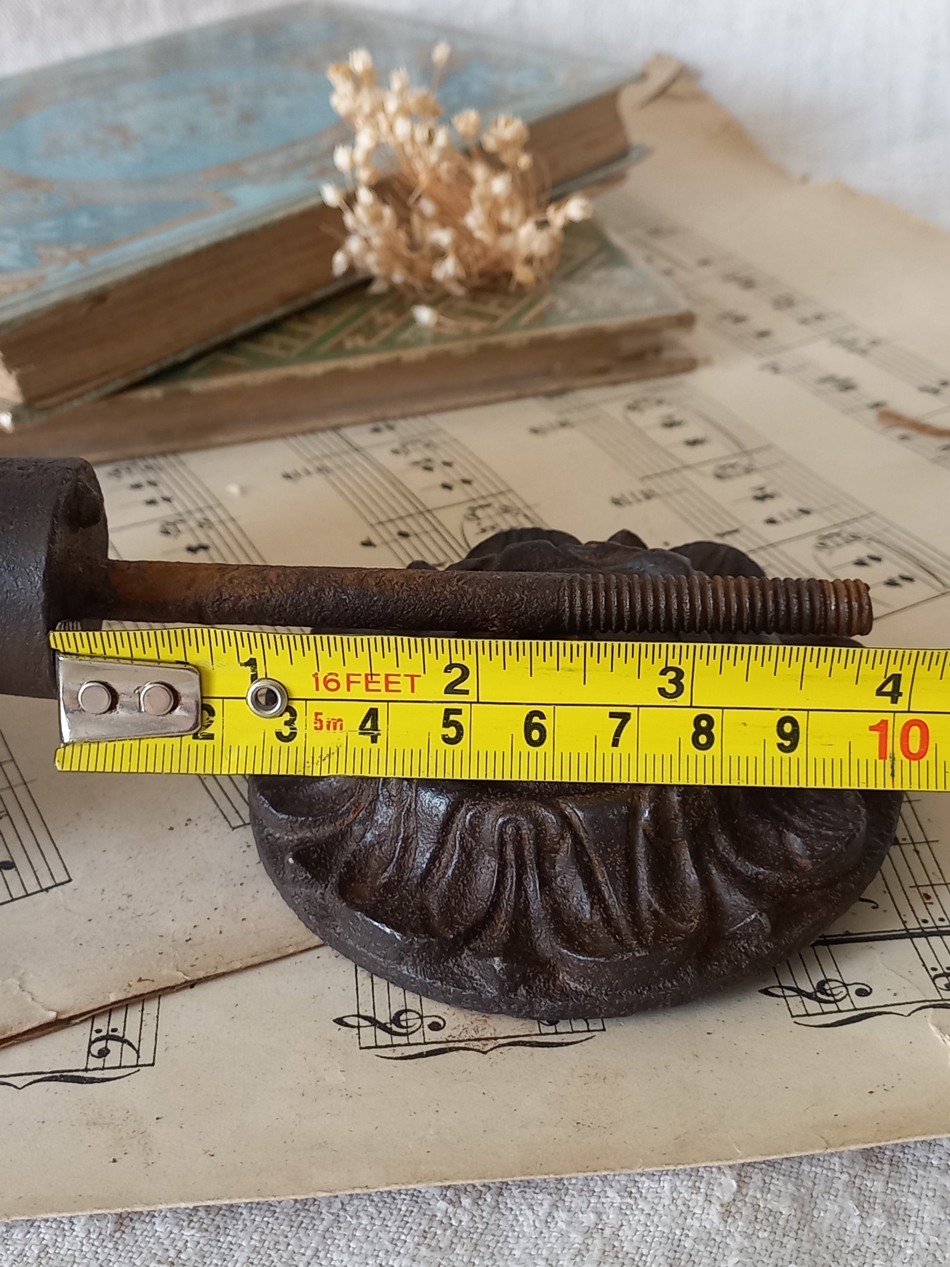 French antique decorative cast iron door pull with tape measure for reference.