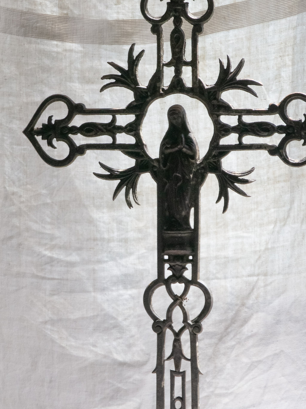 A large French antique crucifix in cast or wrought iron, featuring a figure of the Madonna at its center. Likely once part of a larger architectural structure, this rare piece carries visible signs of age and long exposure to the elements.