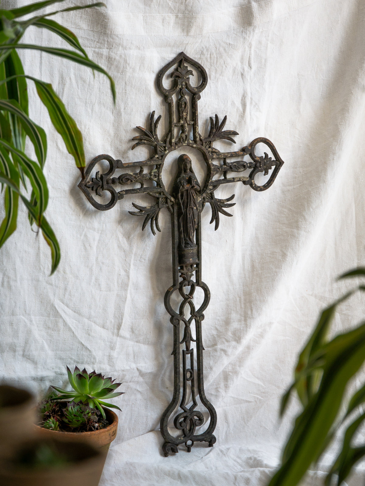A large French antique crucifix in cast or wrought iron, featuring a figure of the Madonna at its center. Likely once part of a larger architectural structure, this rare piece carries visible signs of age and long exposure to the elements.
