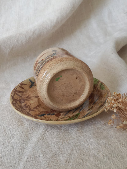 A little antique cup and saucer with oriental influenced design depicting ducks, butterflies, flowers and bamboo shoots.