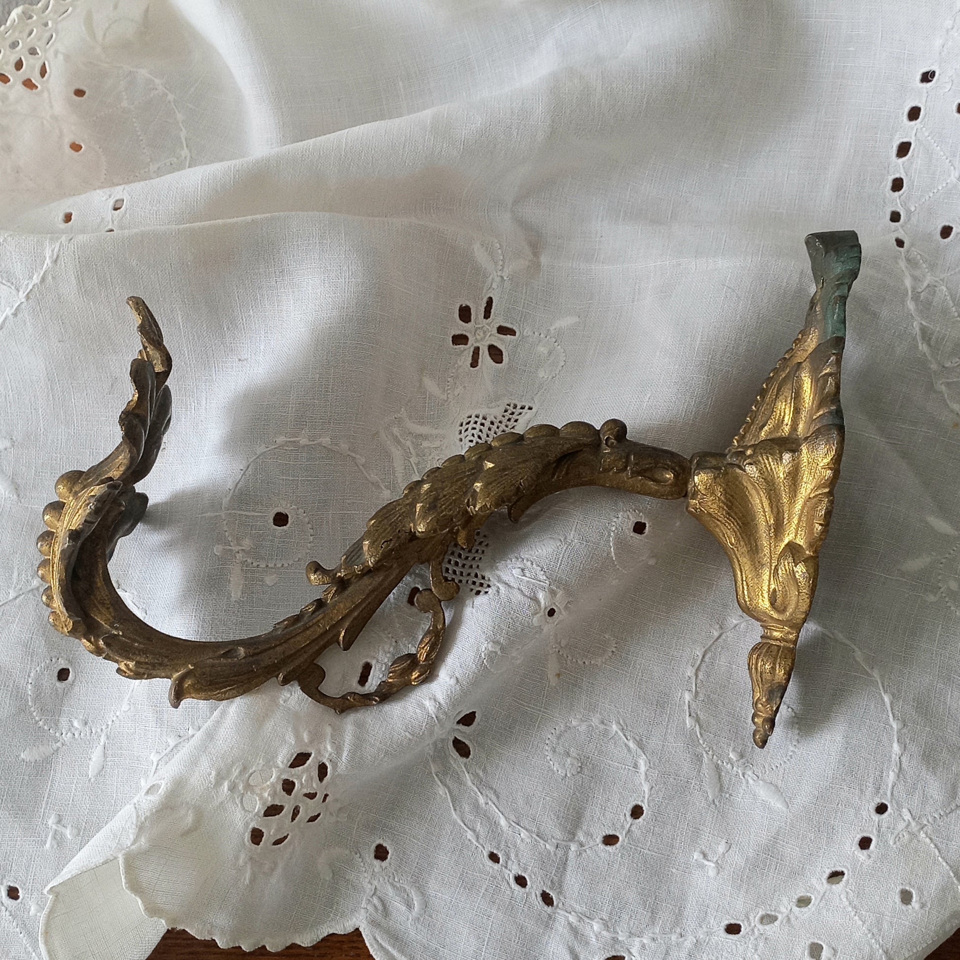 Decorative gold metal bracket on a white lace background