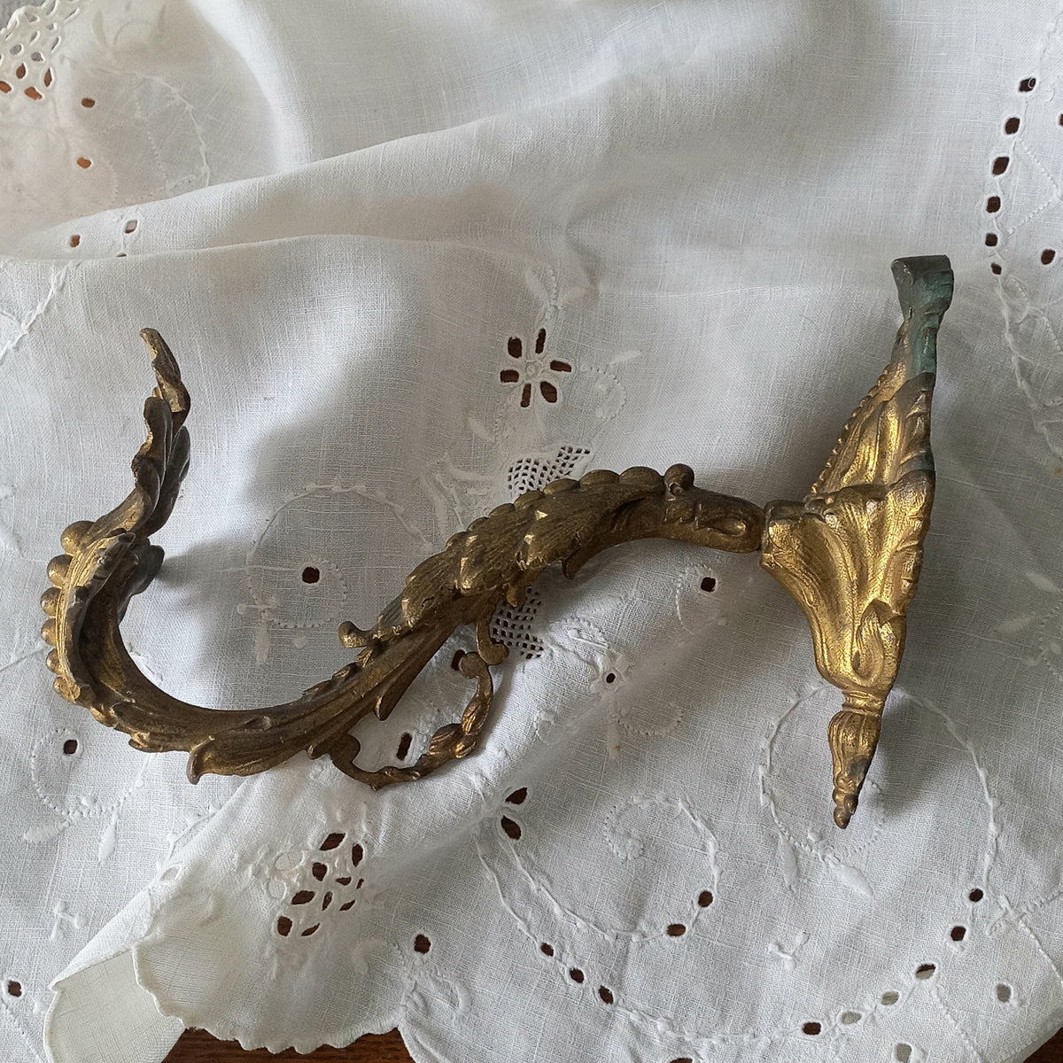 Decorative gold metal bracket on a white lace background