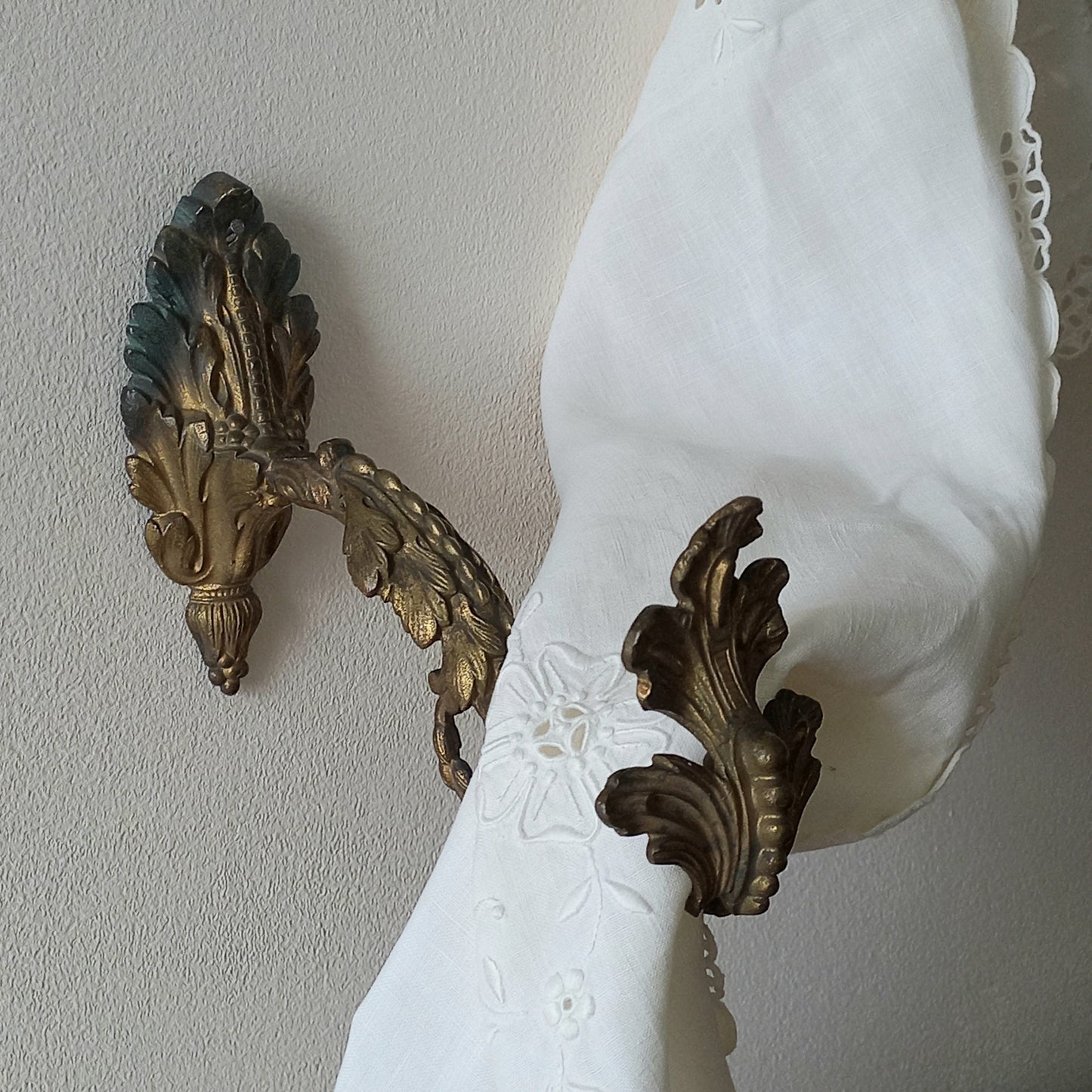 Decorative wall sconces with intricate designs on a plain wall.