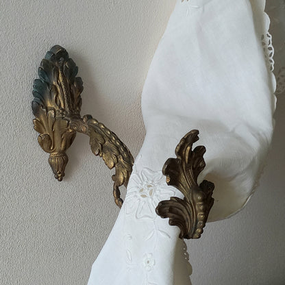 Decorative wall sconces with intricate designs on a plain wall.