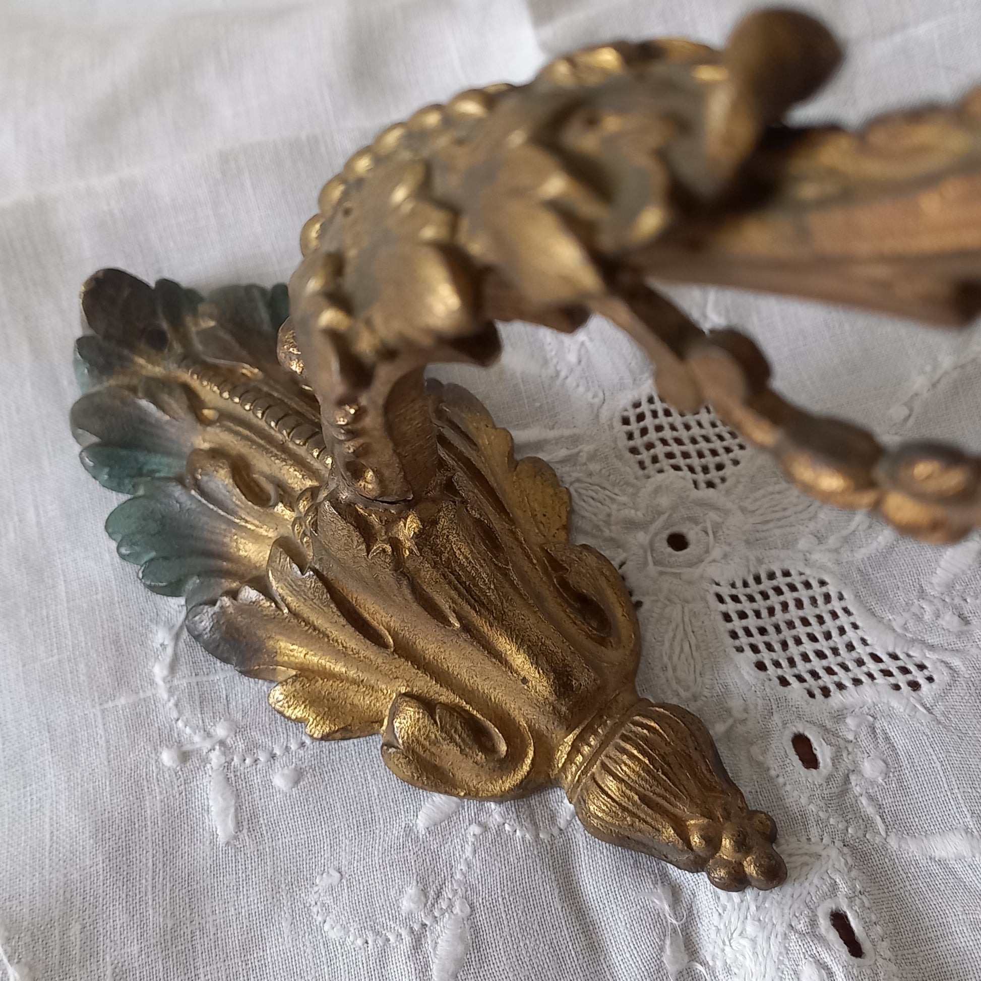 Decorative gold wall sconce on a textured white background