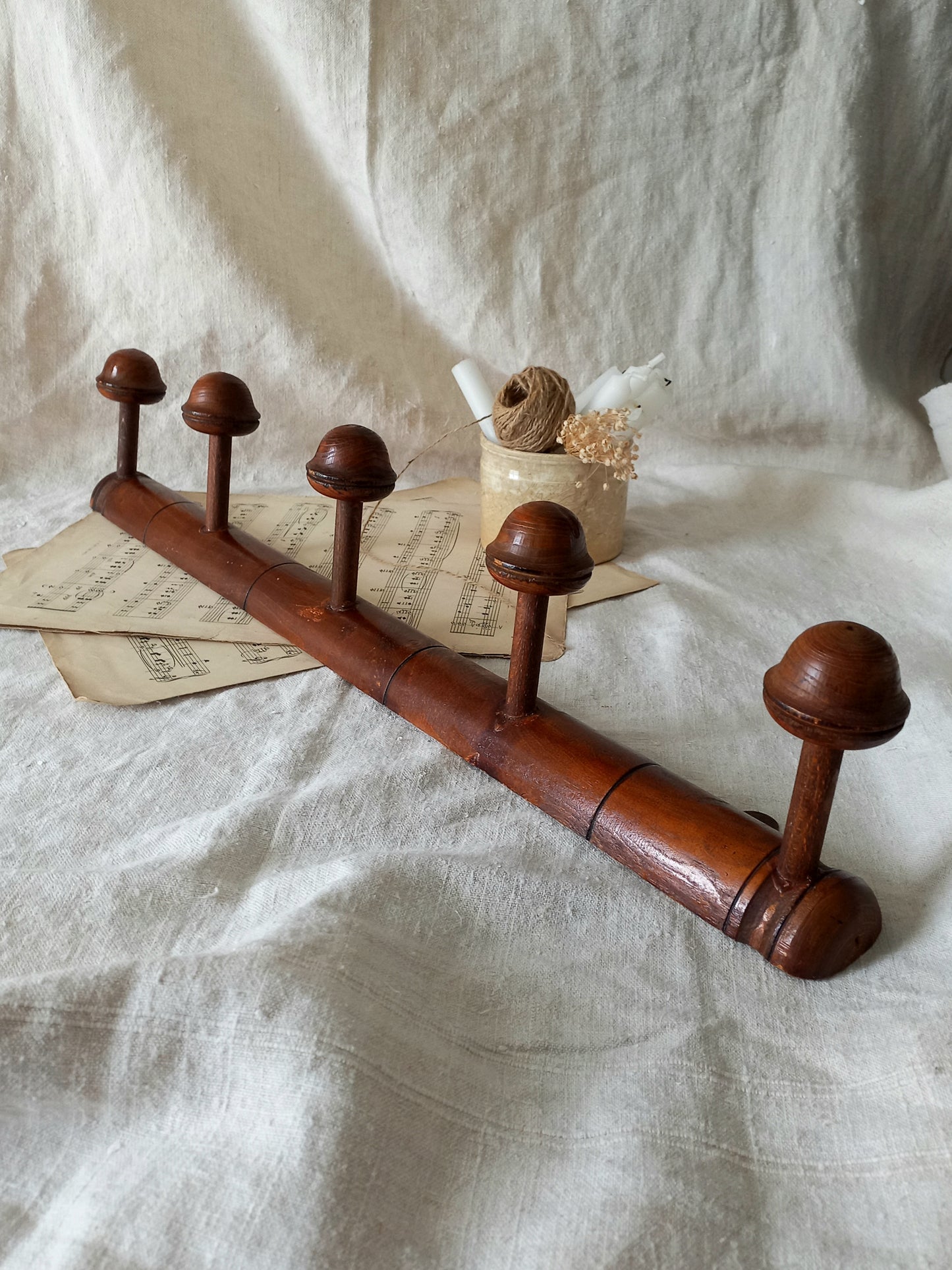 Wooden coat rack with five hooks on a textured white fabric background