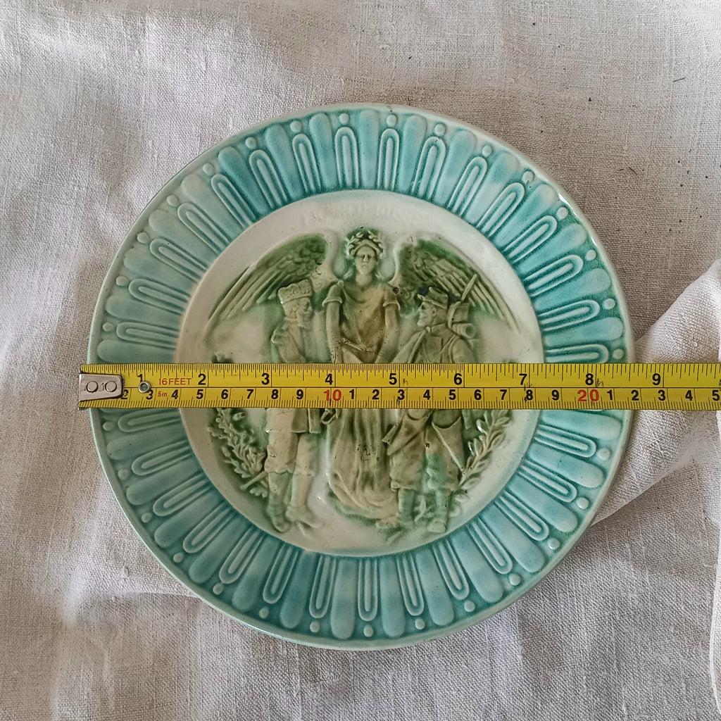 A French antique decorative majolica plate with stunning blue/green colours and an interesting historical background.

This lovely old plate was manufactured as a commemorative piece to celebrate the Franco-Russian Alliance made by the French Republic and the Russian Empire between 1891-1894 (military co-operation agreements) – and that lasted until 1917. The plate depicts a Russian and French soldier shaking hands with a winged female angel in between them.