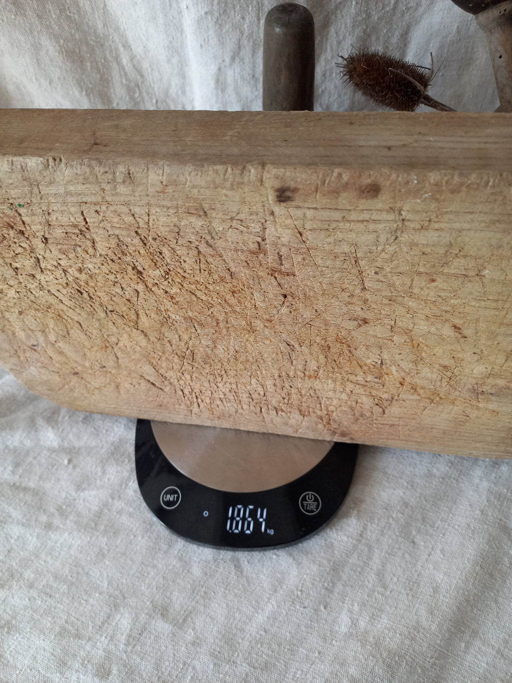 Antique French chunky hand-carved wooden cutting board on a digitial scale for reference.
