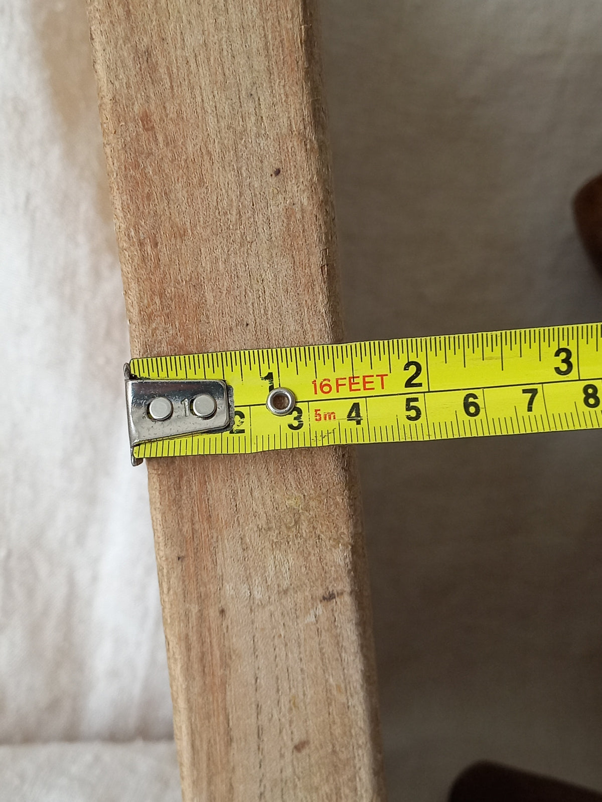 Cllose-up of an antique French chunky hand-carved wooden cutting board with a yellow tape measure for reference.