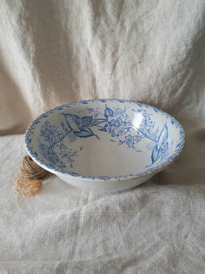 A white ceramic bowl with a blue floral pattern, set against a draped beige linen fabric backdrop.
