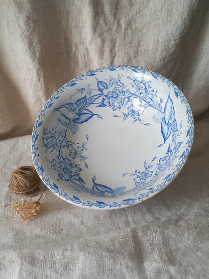 A white ceramic bowl with a blue floral pattern, styled on a beige linen fabric backdrop next to a small ball of twine.