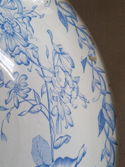 Close-up of a white ceramic bowl featuring a blue floral and leaf pattern, with a small chip visible near the upper right edge.