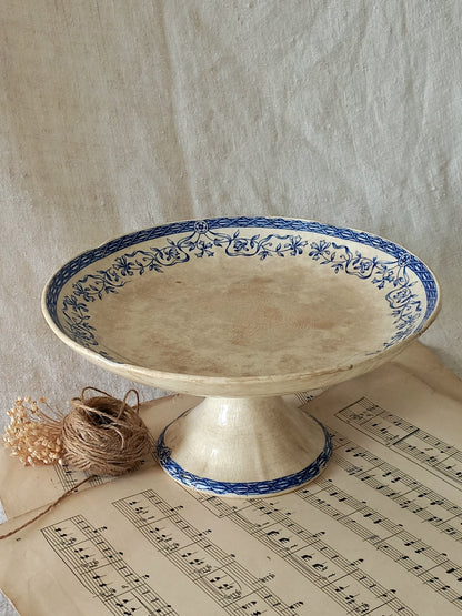 Decorative ceramic pedestal dish with blue floral patterns on a sheet of music.