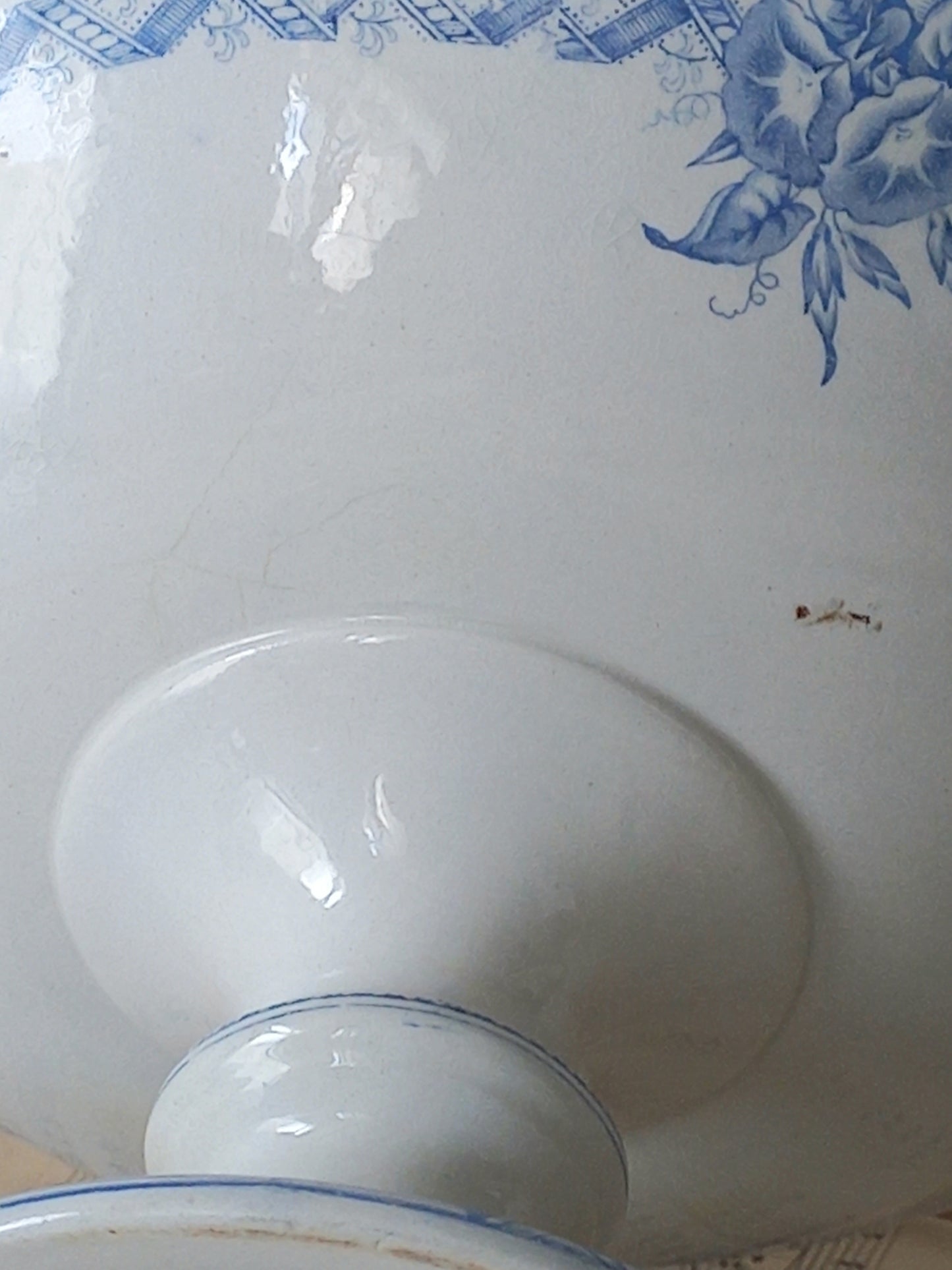 Close-up of a white ironstone footed bowl with a blue floral pattern near the rim and a glossy white pedestal base.