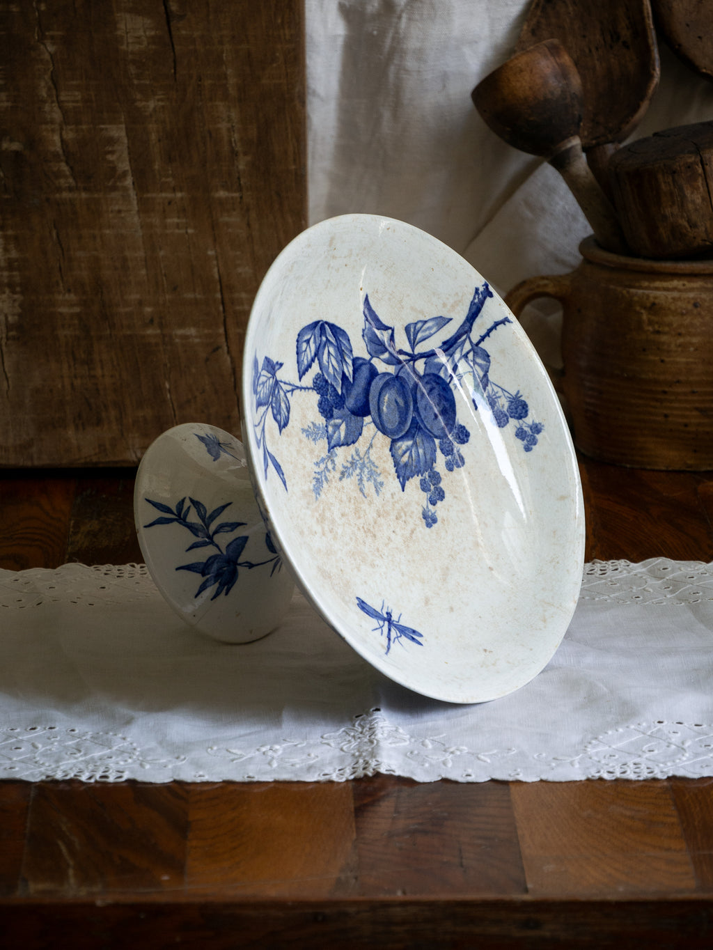 Compotier sur pied en faïence blanche ancienne française, orné d'un motif de libellule bleue et de fleurs. 