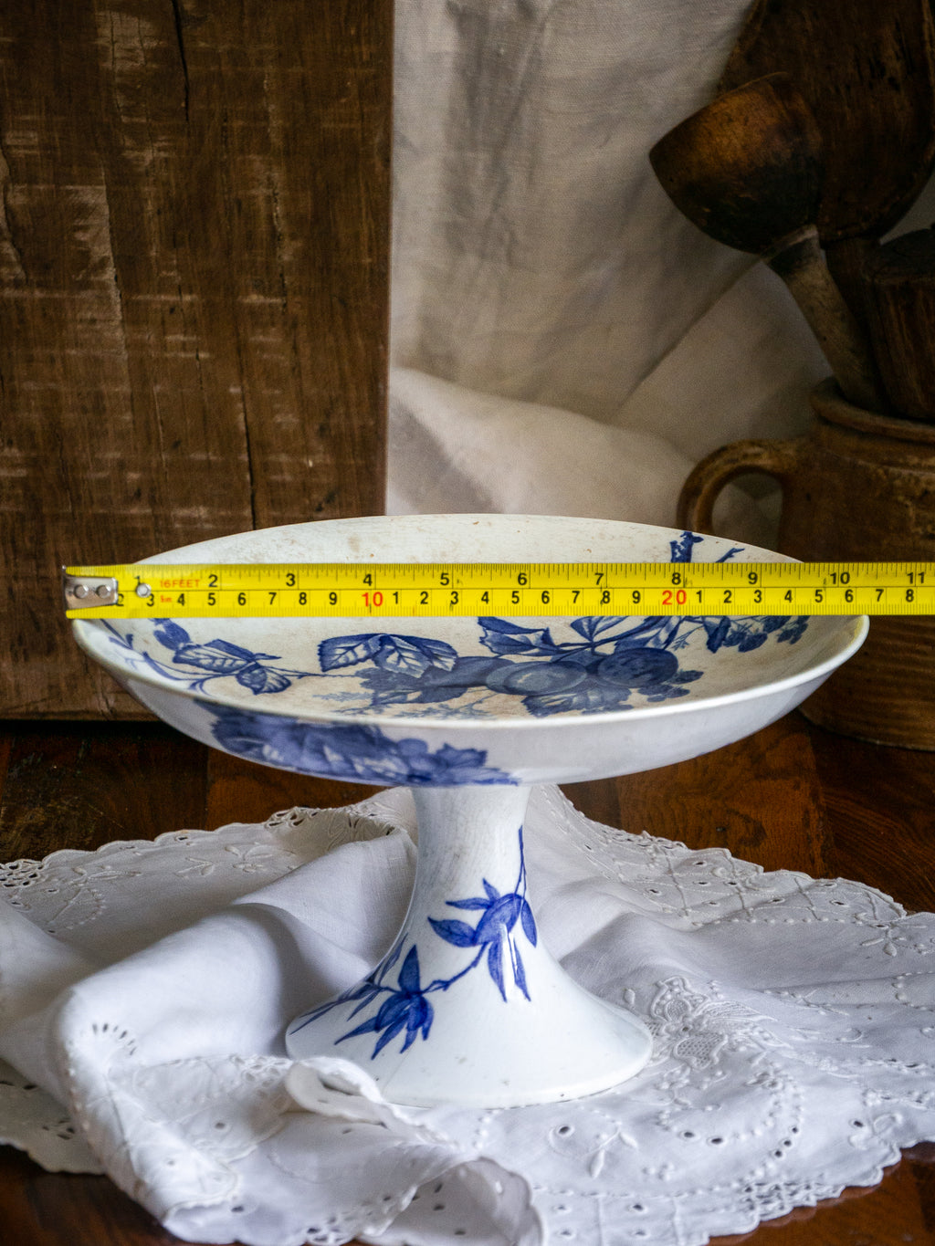 Compotier sur pied en faïence blanche ancienne française, orné d'un motif de libellule bleue et de fleurs. 