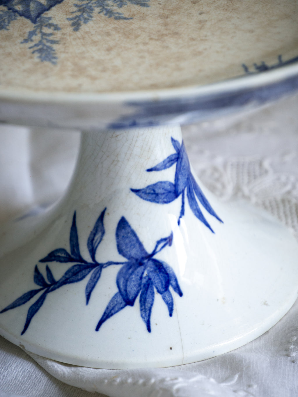 Compotier sur pied en faïence blanche ancienne française, orné d'un motif de libellule bleue et de fleurs. 