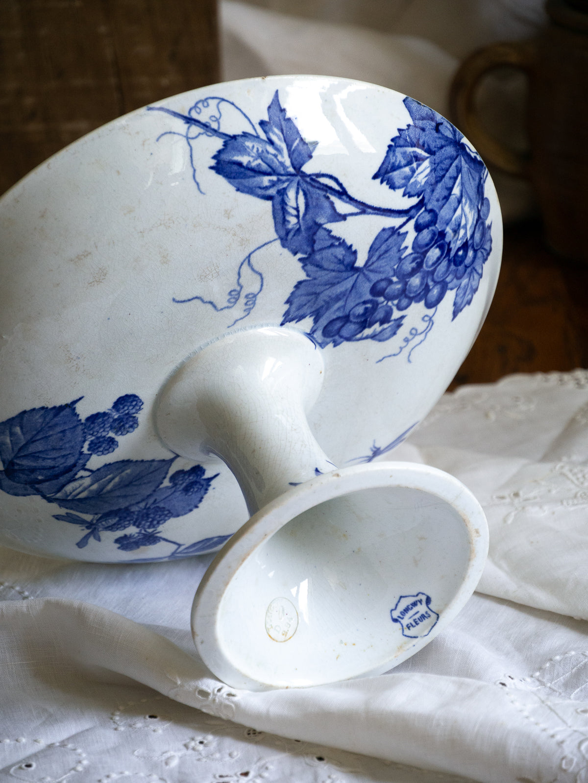 Compotier sur pied en faïence blanche ancienne française, orné d'un motif de libellule bleue et de fleurs. 