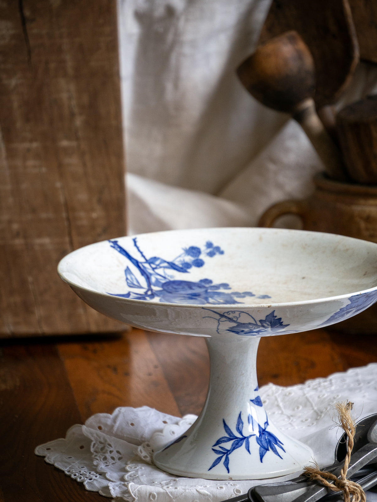Compotier sur pied en faïence blanche ancienne française, orné d'un motif de libellule bleue et de fleurs. 