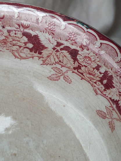 Close-up of a French antique ironstone/earthenware white patinated footed-dish with a pretty burgandy colour floral pattern.