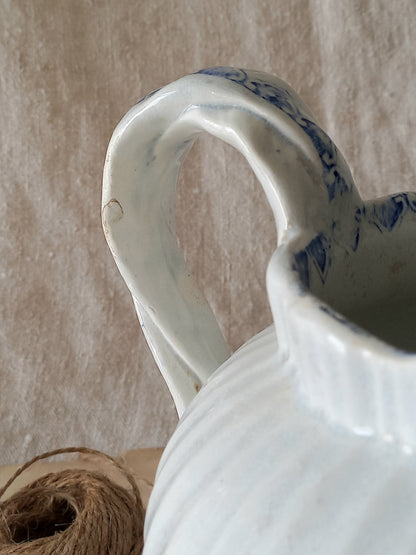 White ceramic pitcher with blue patterns on a textured beige background