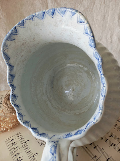 Ceramic jug with blue decorative rim on a surface with music sheet background