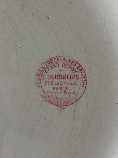 A close-up of a white porcelain surface with a circular red stamp reading E. Bourgeois, Paris