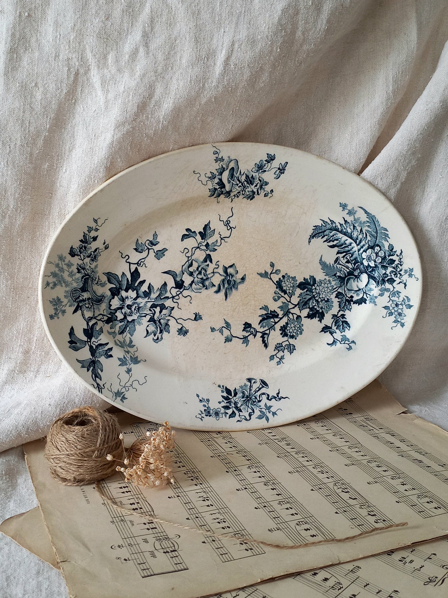 Oval ceramic plate with blue floral patterns on a light fabric background