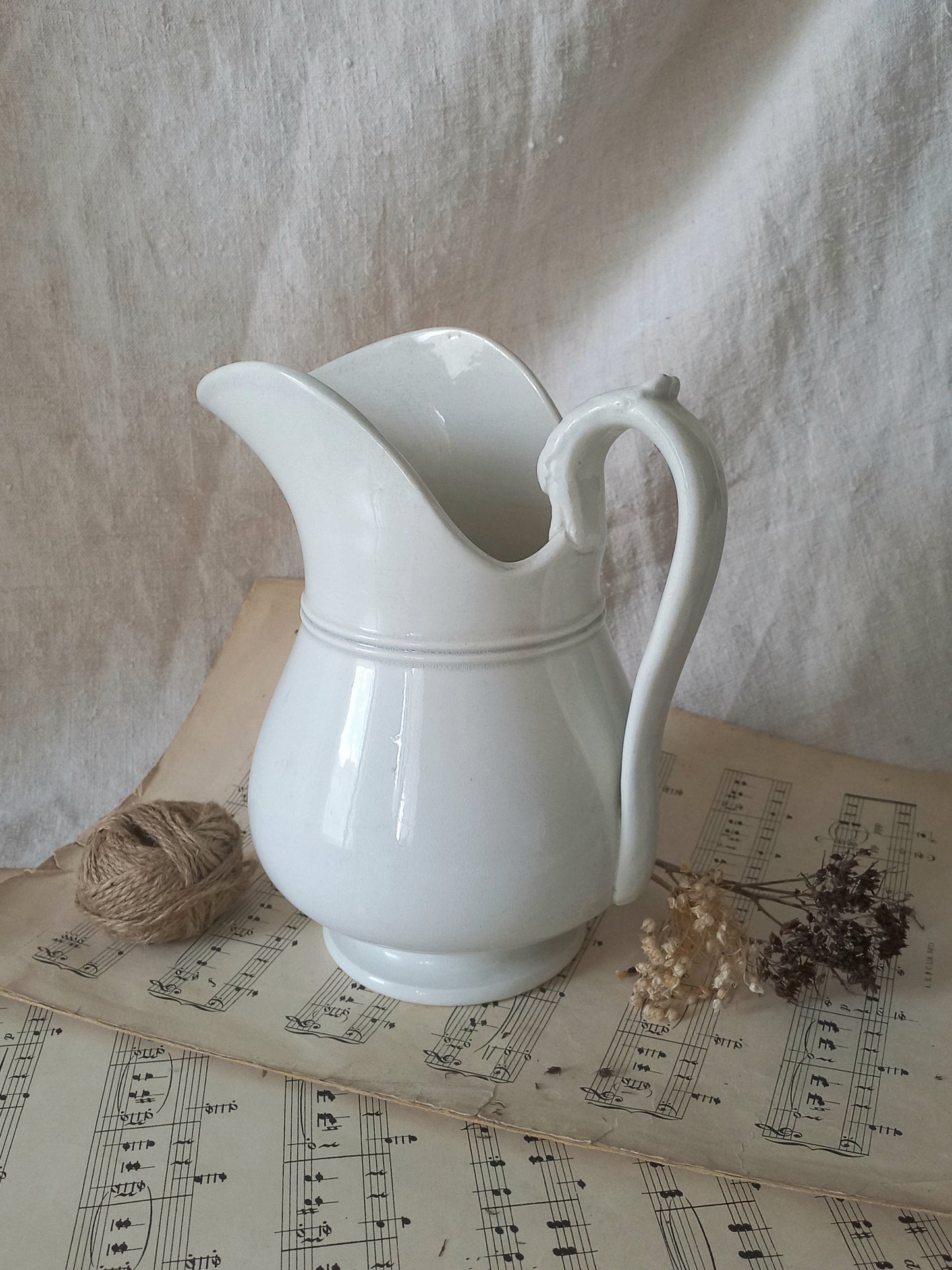 French antique white ironstone jug or pitcher with swan neck handle in a decorative setting.