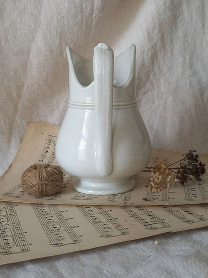 French antique white ironstone jug or pitcher with swan neck handle in a decorative setting.