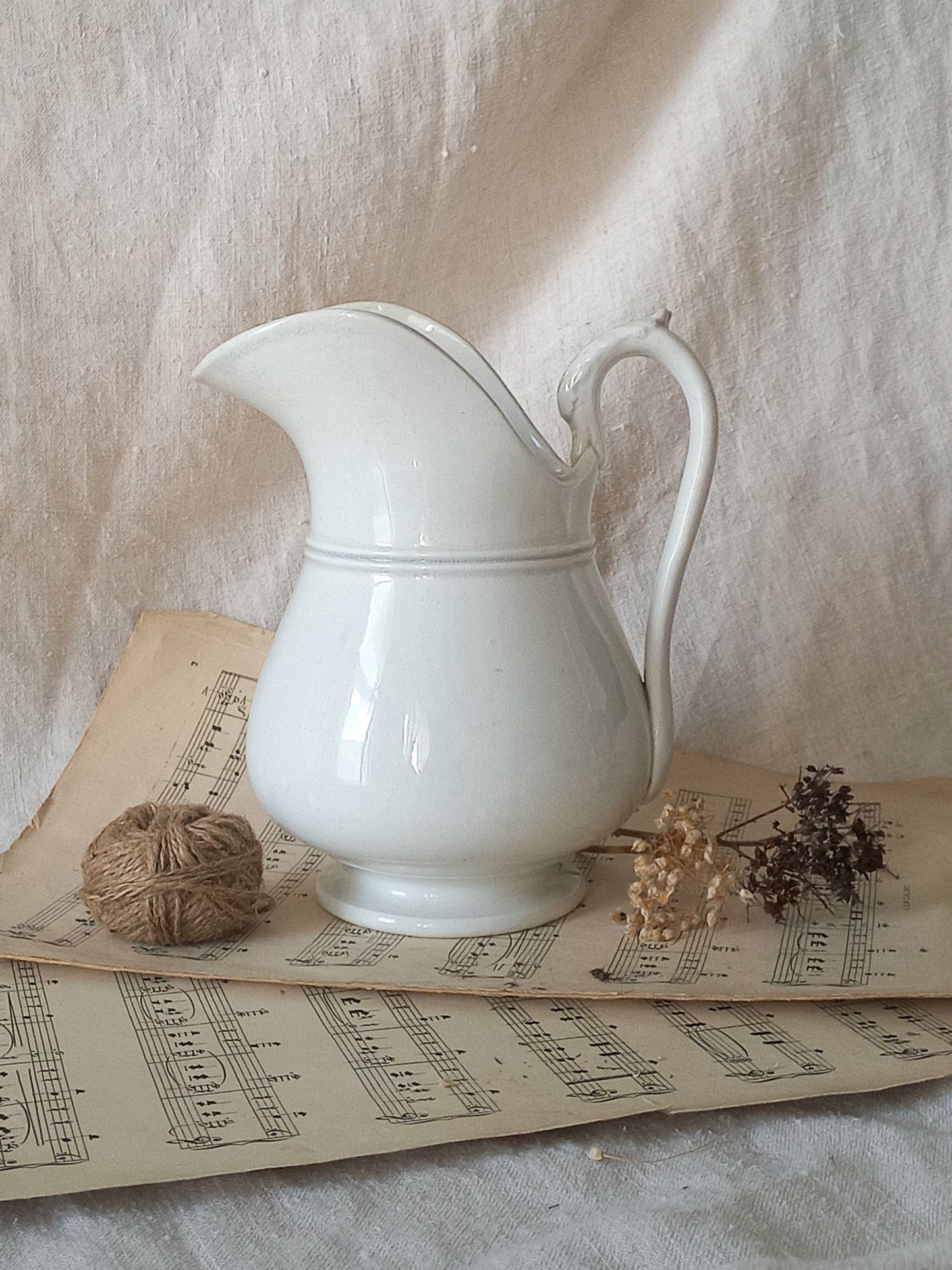  French antique white ironstone jug or pitcher with swan neck handle in a decorative setting.