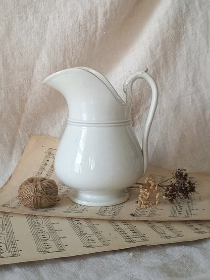 French antique white ironstone jug or pitcher with swan neck handle in a decorative setting.