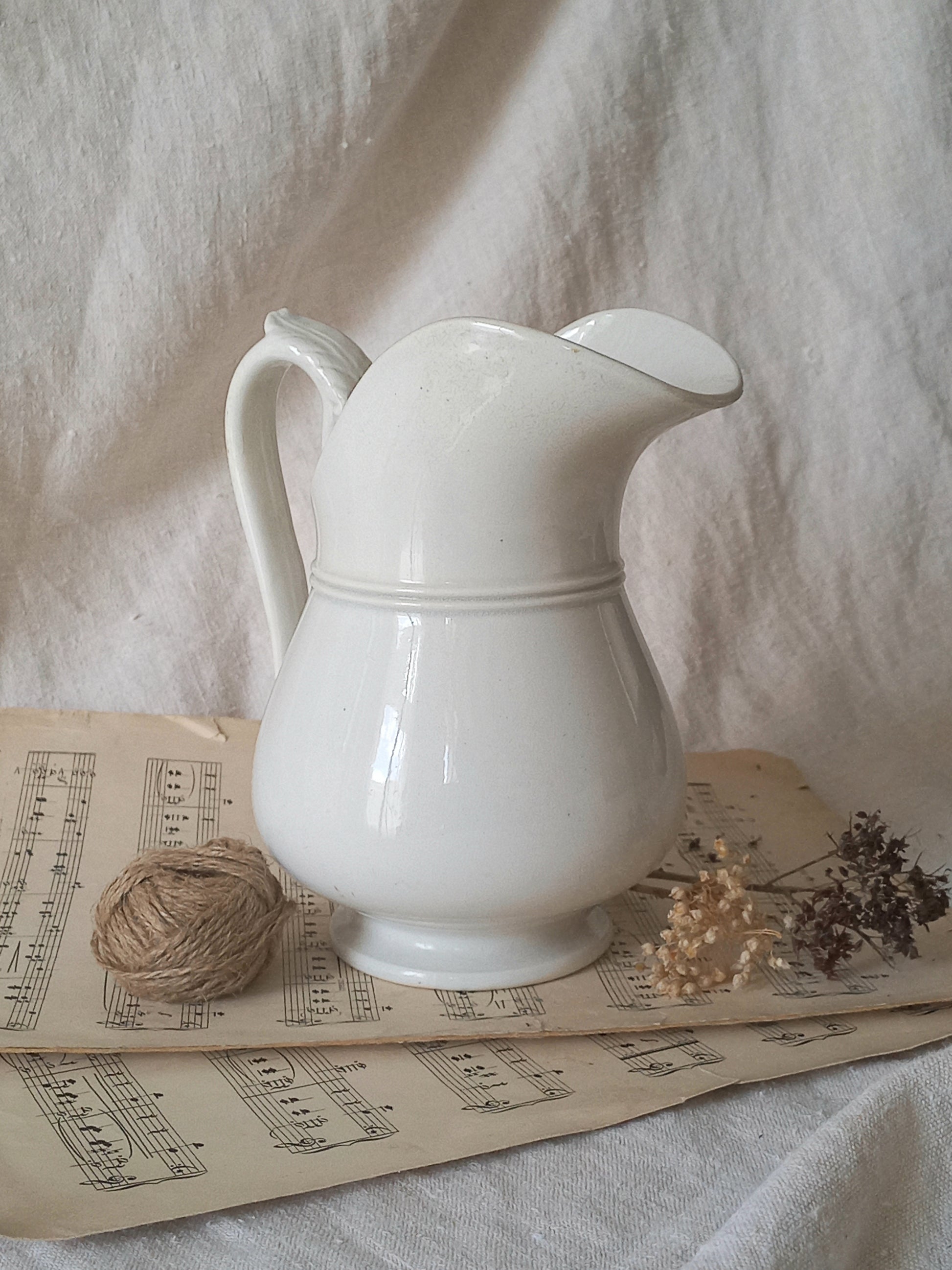 French antique white ironstone jug or pitcher with swan neck handle in a decorative setting.