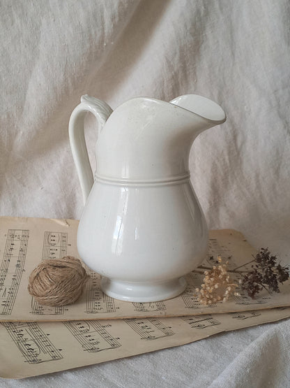 French antique white ironstone jug or pitcher with swan neck handle in a decorative setting.